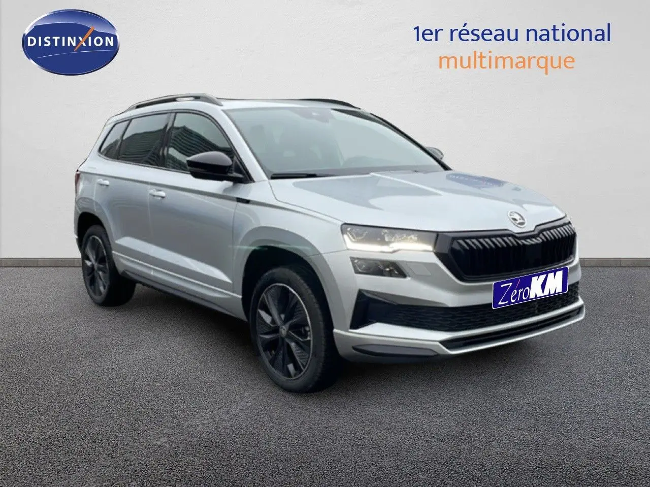 Vue 3/4 avant d’un Skoda Karoq gris argent métal 2025 avec jantes noires et calandre noire sportive.
