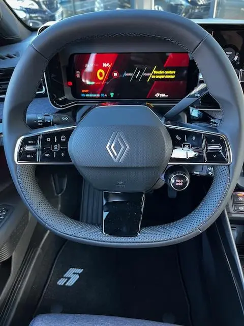 Vue rapprochée du volant noir de la Renault R5 Techno 2024 avec tableau de bord numérique et logo central.
