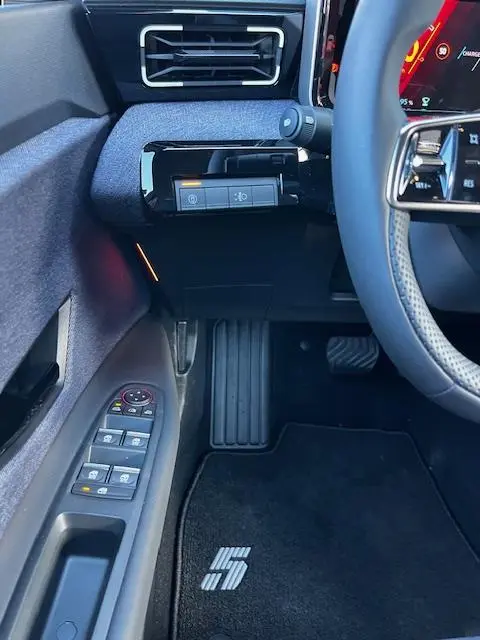 Vue intérieure côté gauche du tableau de bord et porte de la Renault R5 Techno jaune 2024, avec commandes électriques et tapis marqué "5".