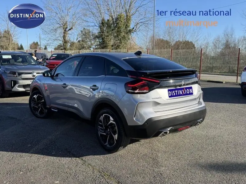 Vue 3/4 arrière droite d'une Citroën C4 2024 gris acier avec toit noir et jantes distinctives en concession.