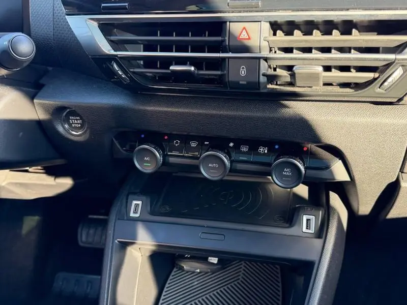 Vue rapprochée de la console centrale de la Citroën C4 2024 gris acier, montrant les commandes de climatisation et le bouton start/stop.