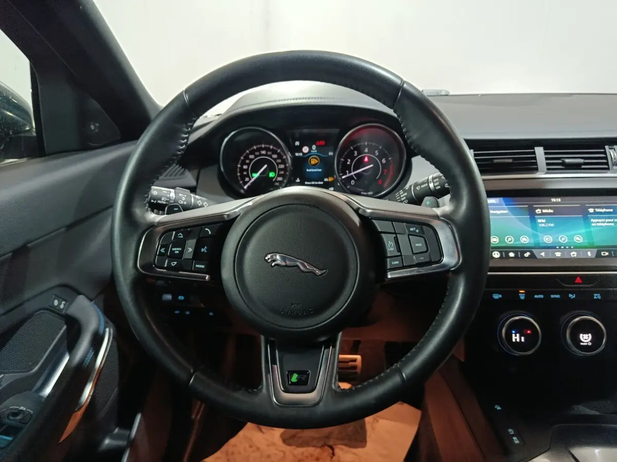 Vue intérieure centrée sur le volant cuir noir multifonctions du Jaguar E-PACE 2019 avec tableau de bord et écran tactile.