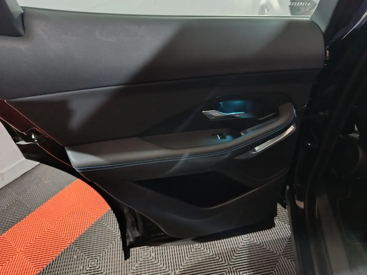 Vue intérieure côté gauche de la porte arrière noire du Jaguar E-PACE avec éclairage bleu et surpiqûres contrastantes.