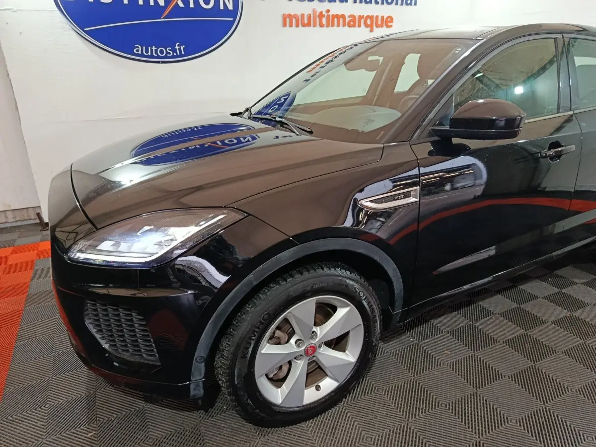 Vue 3/4 avant droit d'un Jaguar E-PACE noir brillant, mettant en valeur ses phares LED et la calandre sportive.