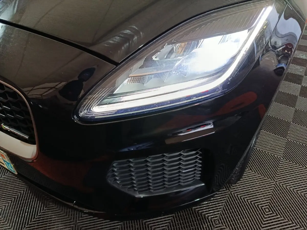 Gros plan sur l'avant droit noir brillant du Jaguar E-PACE 2019, mettant en valeur le phare LED et la calandre.