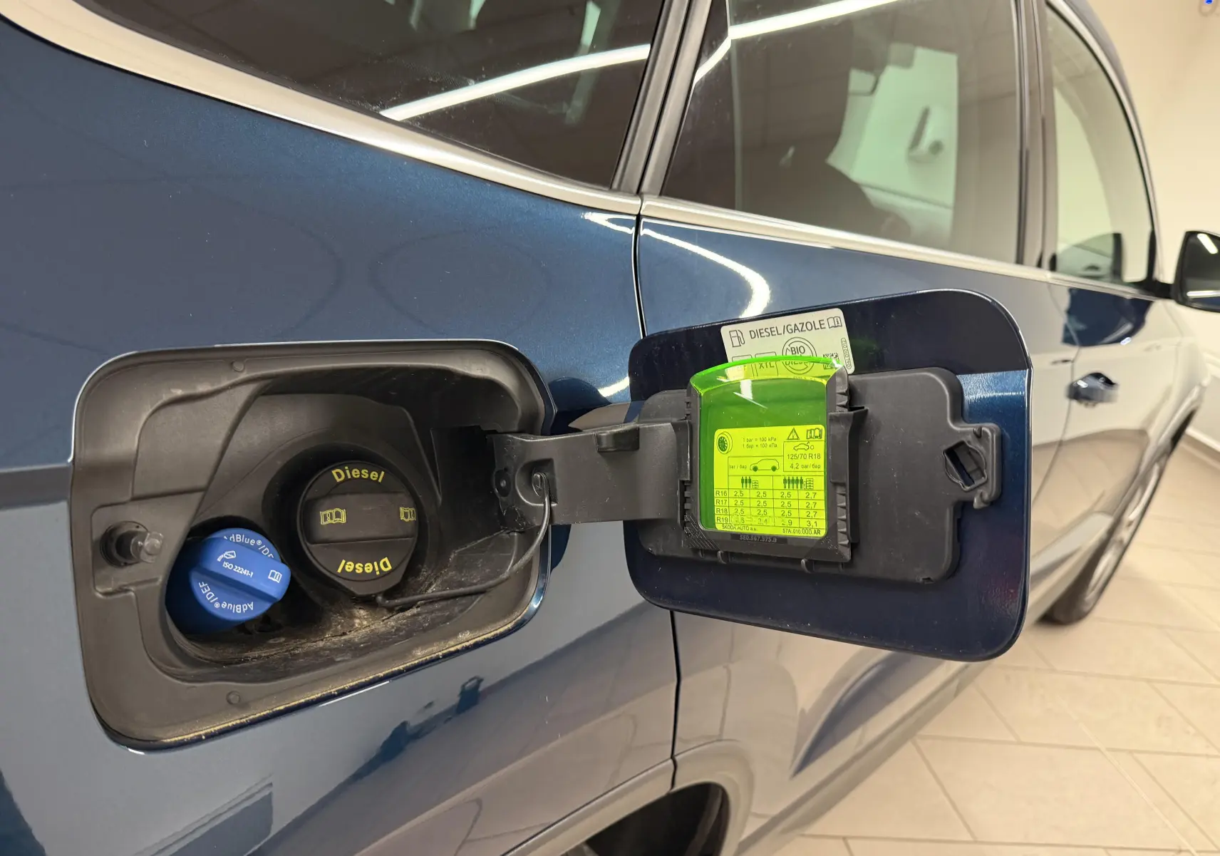 Vue rapprochée de la trappe à carburant côté gauche du Skoda Karoq bleu lave avec bouchon diesel et AdBlue visible.