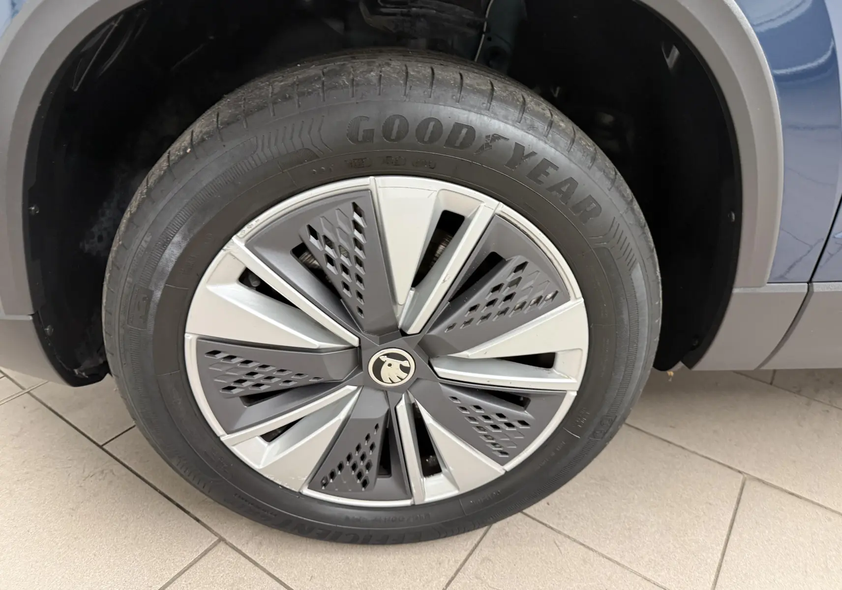 Gros plan sur la roue avant droite du Skoda Karoq bleu lave, avec jante stylisée et pneu Goodyear visible.