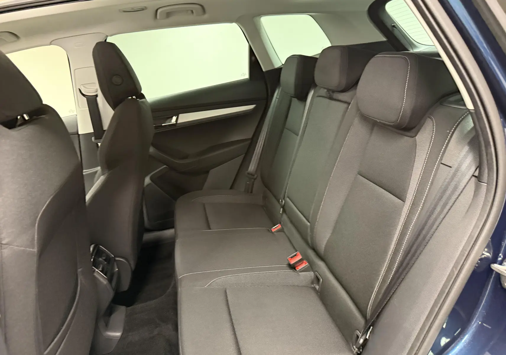 Vue intérieure côté droit des sièges arrière noirs du Skoda Karoq 2023 bleu lave avec ceinture et appuie-têtes visibles.