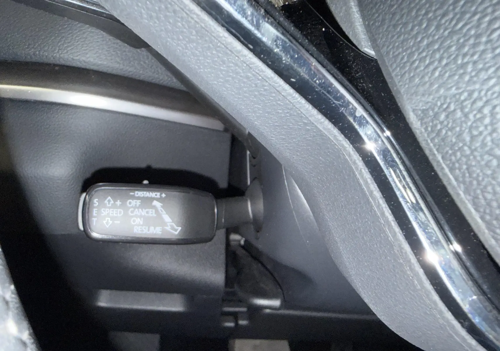 Gros plan sur la commande de régulateur de vitesse du Skoda Karoq 2023, intérieur noir avec détails chromés.