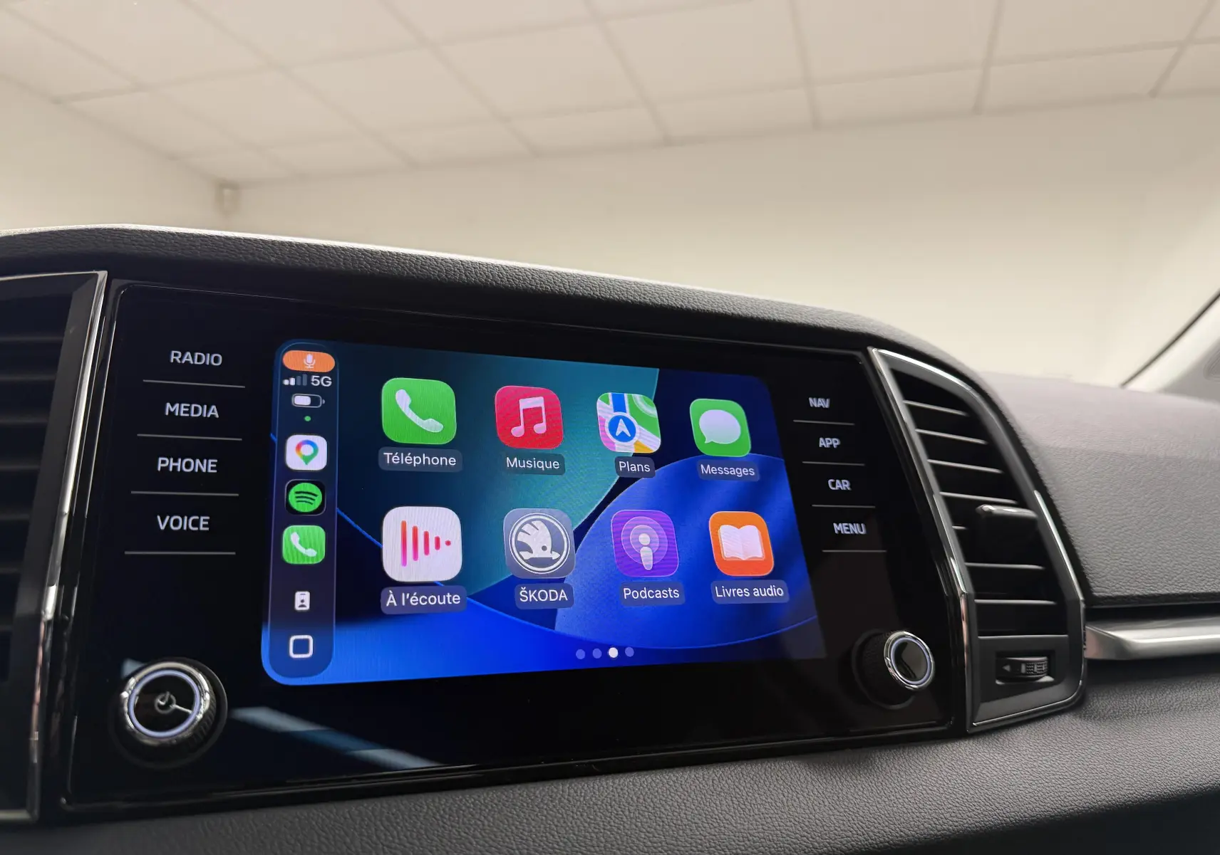 Écran tactile central du Skoda Karoq 2023 affichant Apple CarPlay avec commandes latérales visibles.