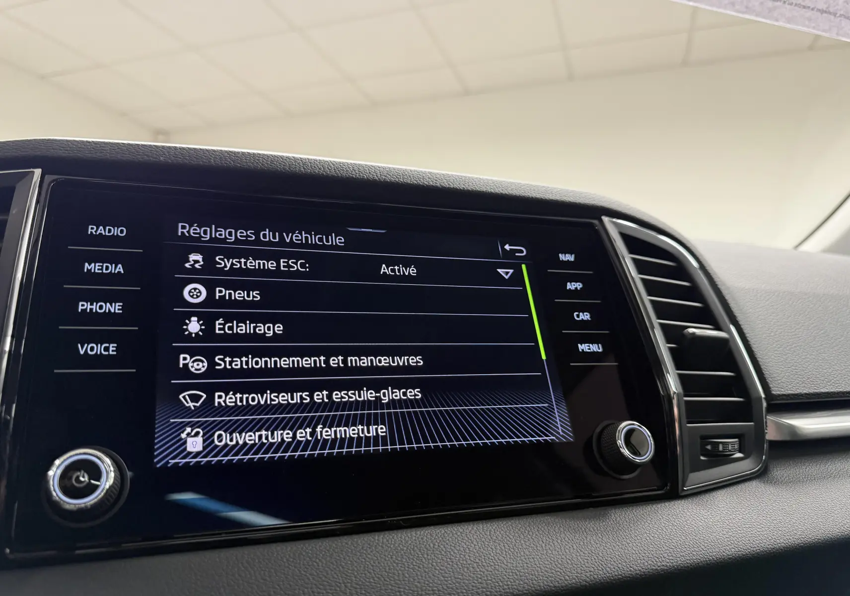 Écran tactile du tableau de bord du Skoda Karoq 2023 affichant les réglages du véhicule, vue intérieure côté conducteur.