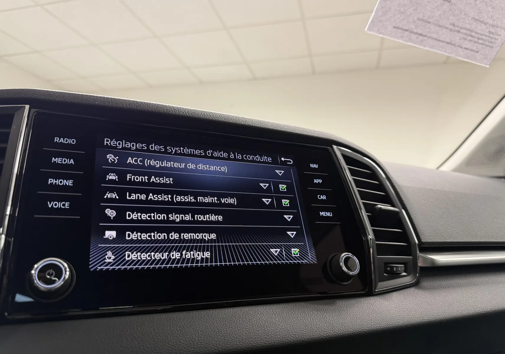 Écran tactile du système d'aide à la conduite dans l'habitacle d'un Skoda Karoq 2023, affichant plusieurs options activées.