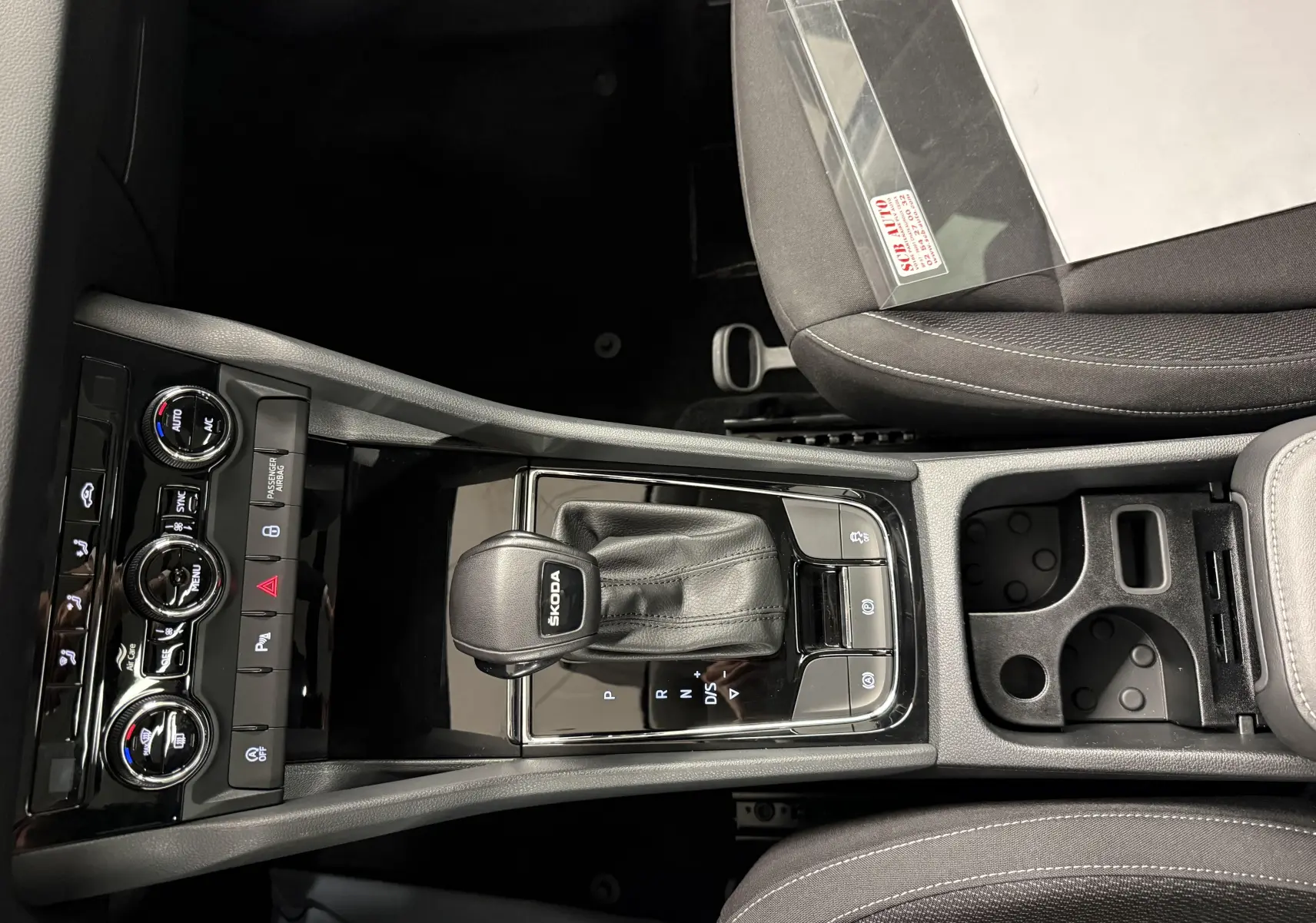 Vue plongeante sur la console centrale du Skoda Karoq 2023, avec levier de vitesses automatique et commandes climatisation.
