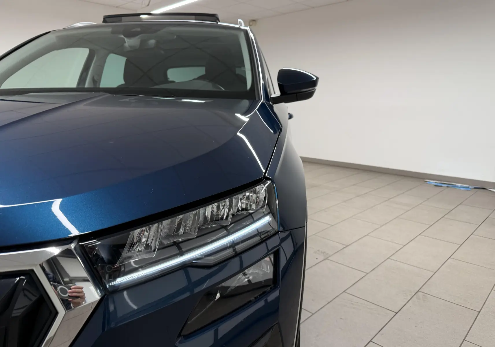 Vue rapprochée 3/4 avant droit du Skoda Karoq bleu lave mettant en valeur le phare LED et le rétroviseur.