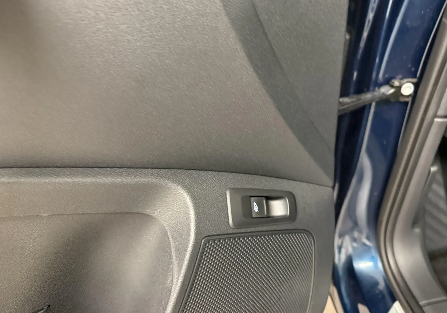 Détail de la portière côté conducteur du Skoda Karoq bleu lave 2023 avec bouton d'ouverture du coffre visible.