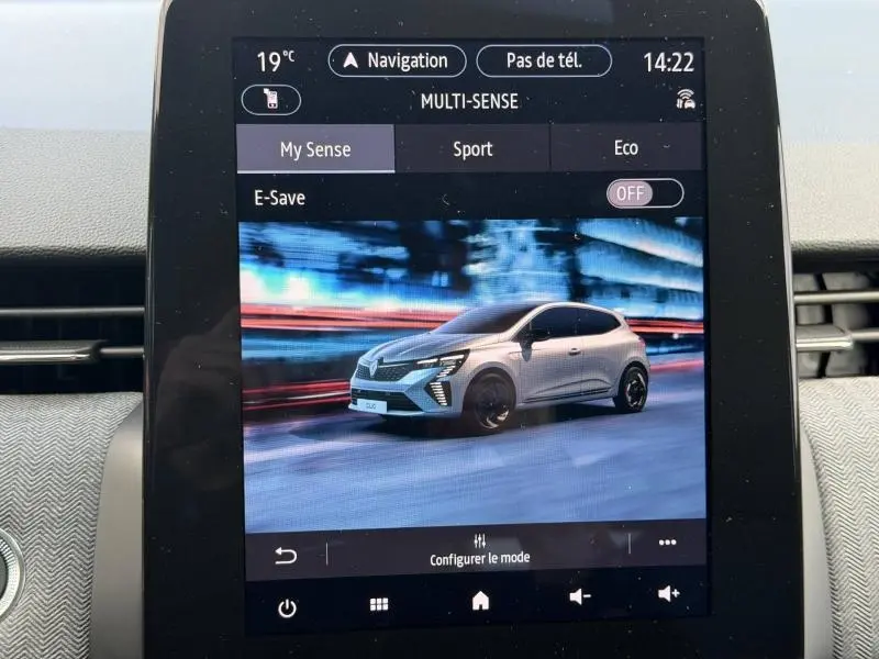 Écran tactile montrant une Renault Clio 2025 blanche en 3/4 avant dans un environnement urbain flouté.