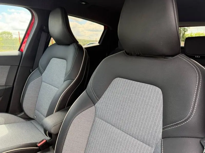 Gros plan sur les sièges avant en tissu gris et cuir noir de la Renault Clio 1.6 E-Tech 145ch rouge Flamme, vue côté conducteur.