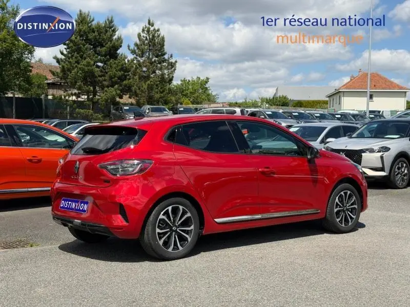 Vue 3/4 arrière droite d'une Renault Clio 1.6 E-Tech hybride Rouge Flamme garée en extérieur sur un parking.