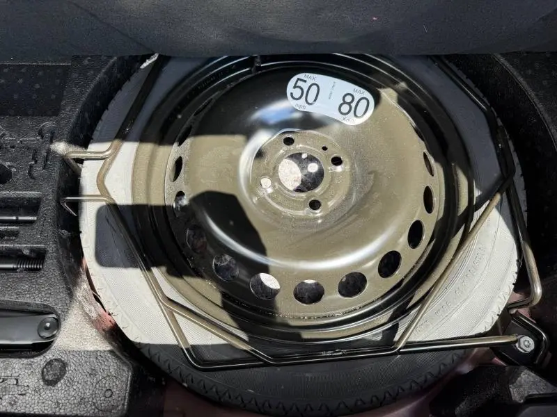 Gros plan sur la roue de secours et le cric dans le coffre d'une Renault Clio 1.6 E-Tech 145ch hybride Rouge Flamme 2025.