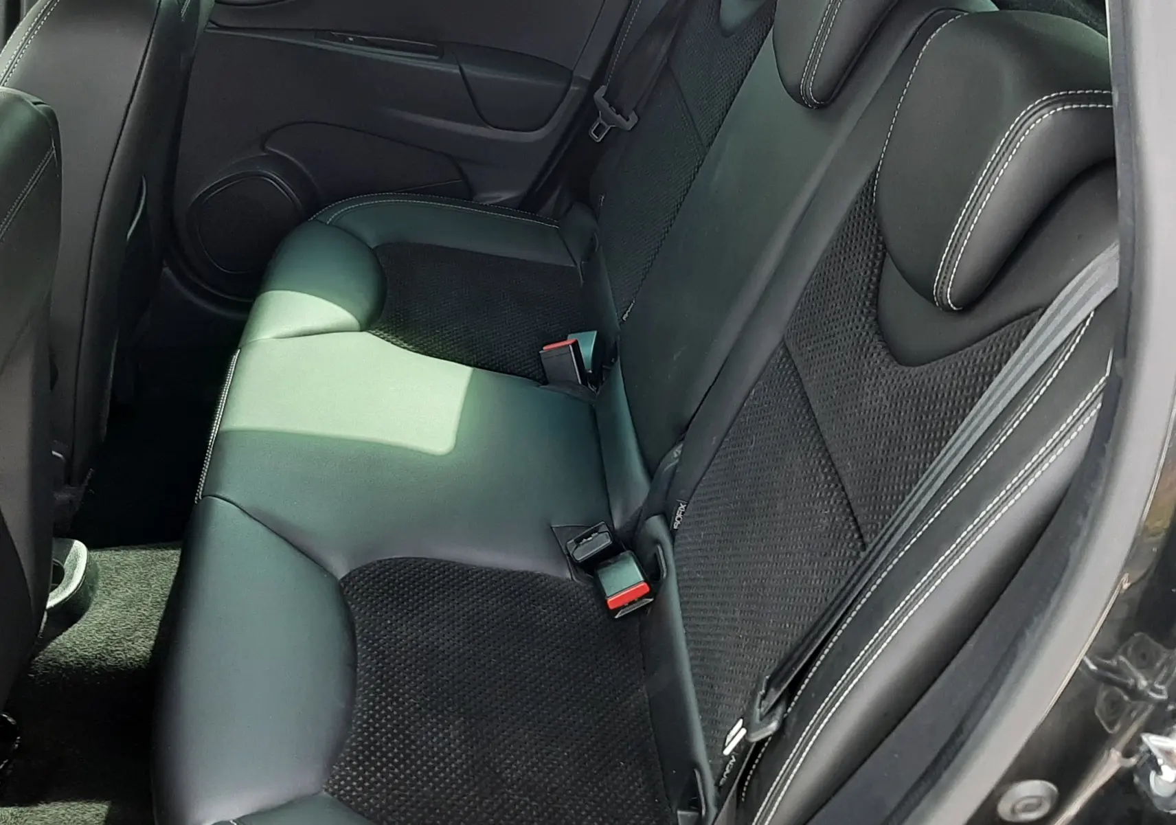 Vue intérieure côté arrière droit montrant la banquette noire en cuir et tissu avec surpiqûres blanches d'une Renault Clio IV 2018.