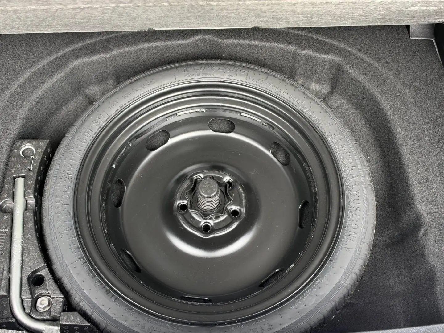Roue de secours noire dans le coffre d'une Volkswagen Golf 1.5 eTSI EVO2 blanche, vue en plongée.