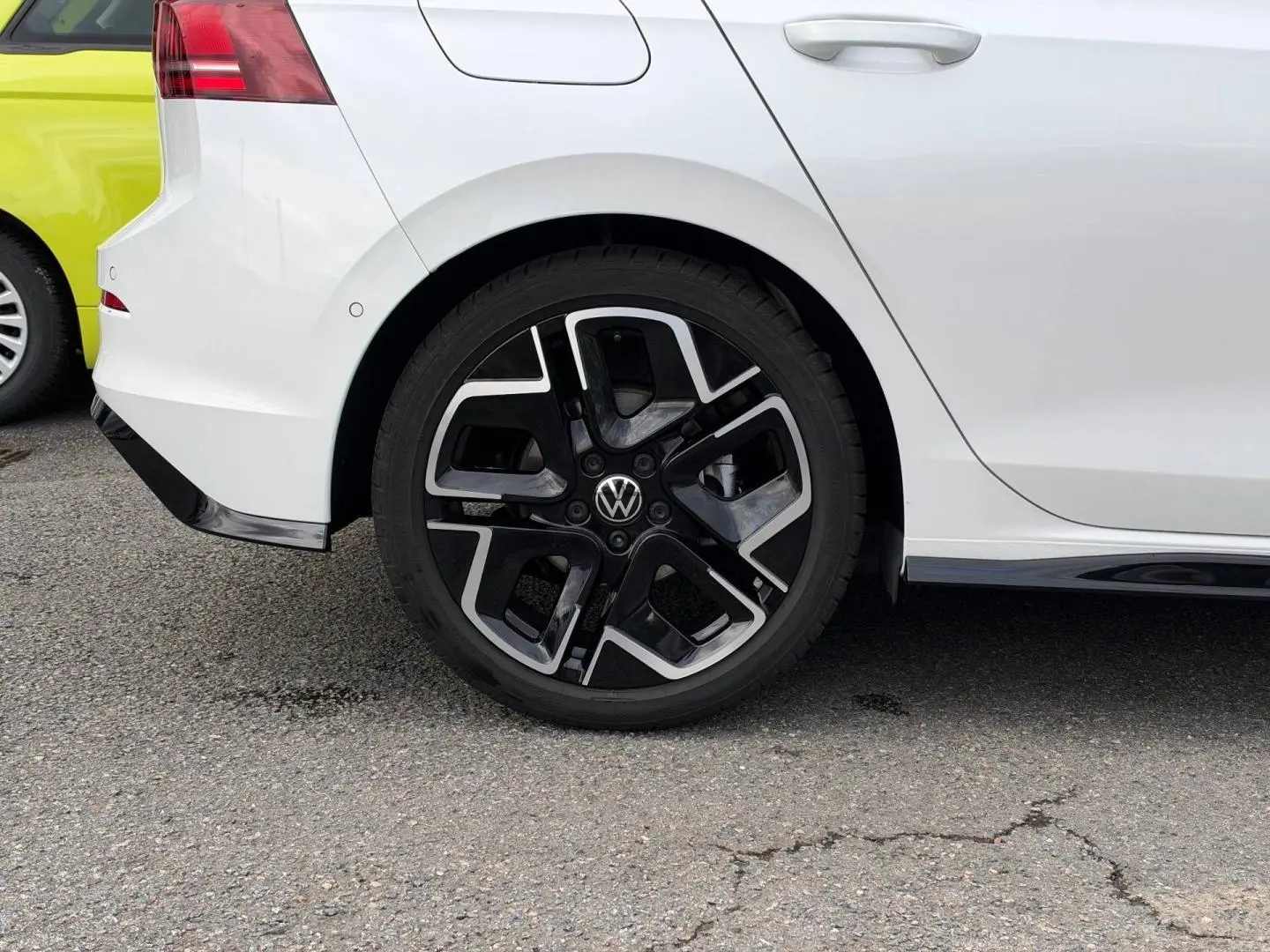 Vue latérale droite sur la roue arrière d’une Volkswagen Golf blanche Oryx nacrée avec jante alu noire et argentée.