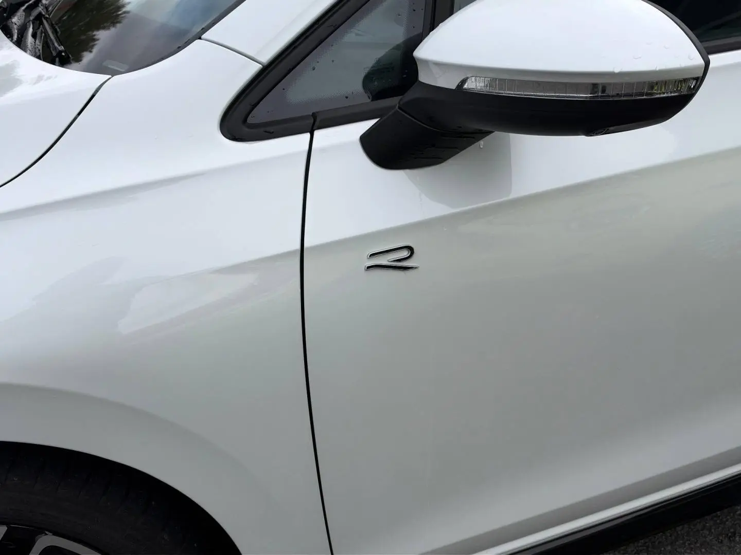 Détail du côté gauche d'une Volkswagen Golf R-Line blanche Oryx nacrée avec rétroviseur et logo R.