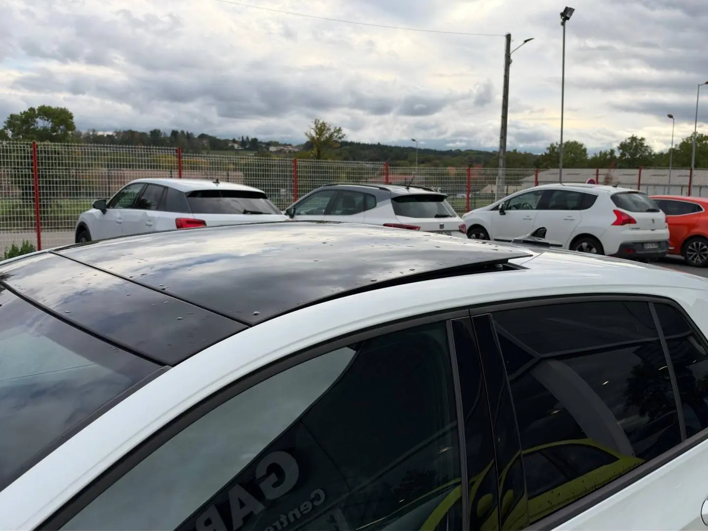 Vue de dessus côté gauche d'une Volkswagen Golf blanche Oryx nacrée avec toit ouvrant panoramique noir partiellement ouvert.
