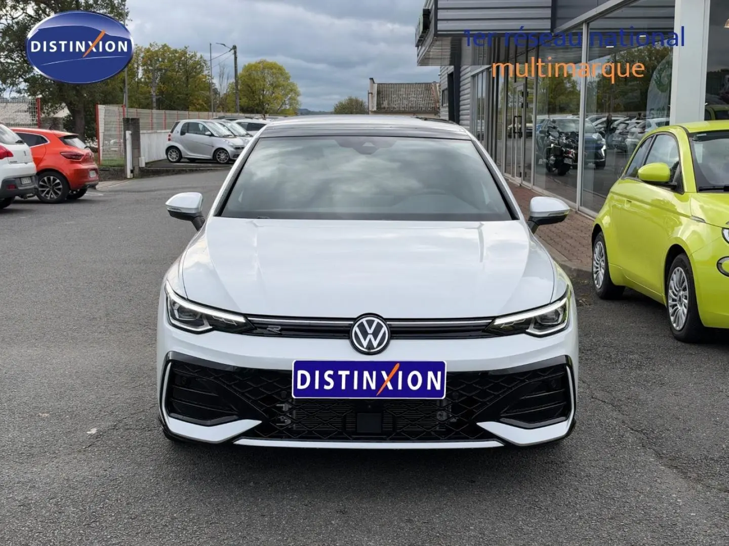 Vue frontale d'une Volkswagen Golf blanche Oryx nacrée avec calandre noire et logo VW bien visible.