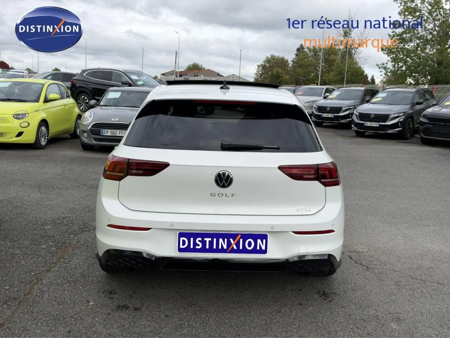 Vue arrière d'une Volkswagen Golf 1.5 eTSI EVO2 blanche Oryx nacrée avec vitres arrière surteintées sur un parking.