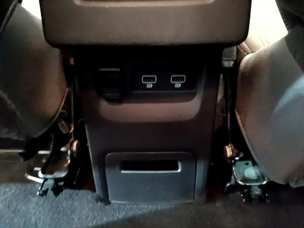 Prise USB double et prise 12V sous l'accoudoir entre les sièges arrière du Renault Kangoo bleu 2023.