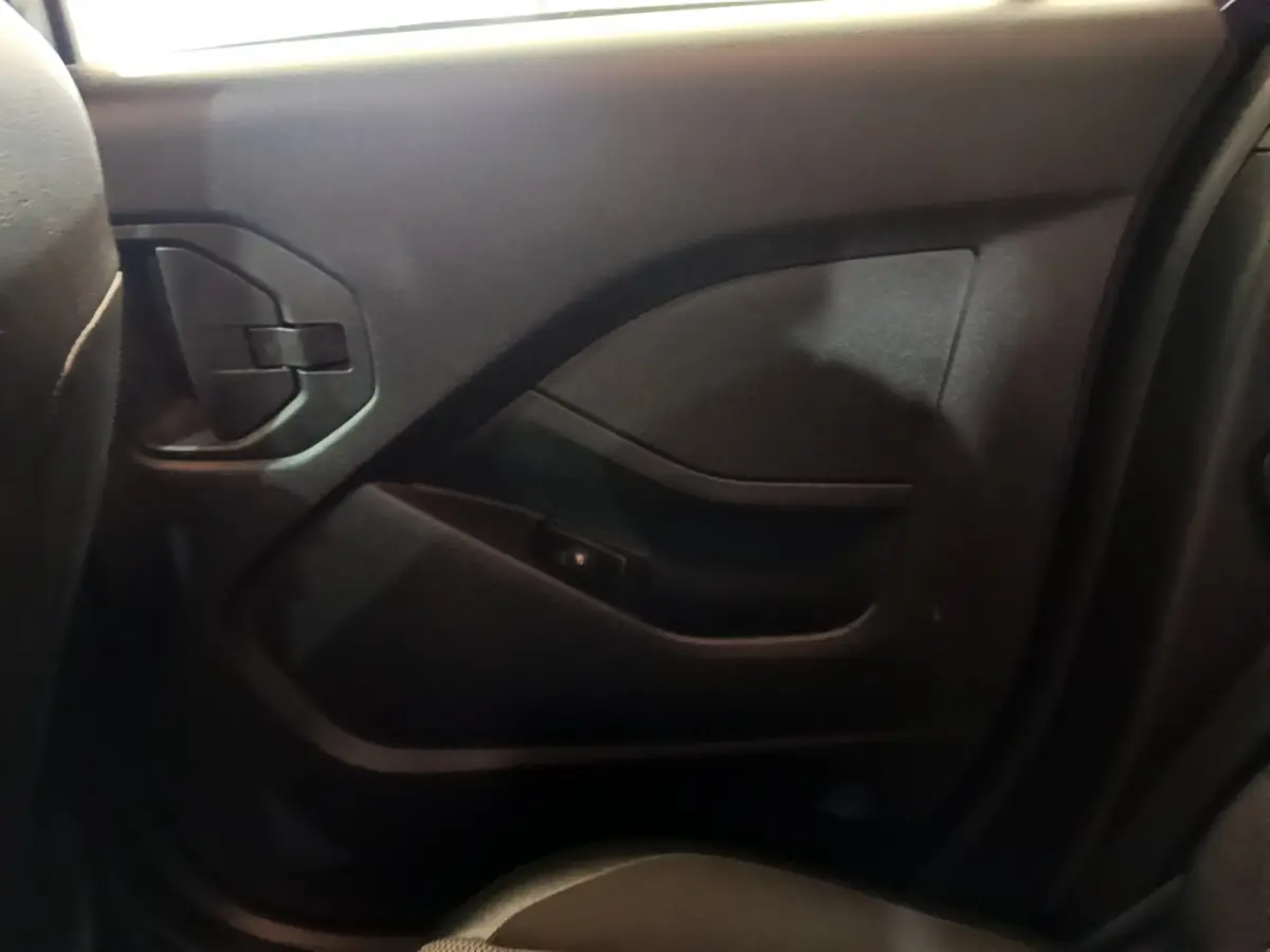 Gros plan sur la porte arrière droite intérieure noire du Renault Kangoo Equilibre 2023, avec poignée intégrée et accoudoir.