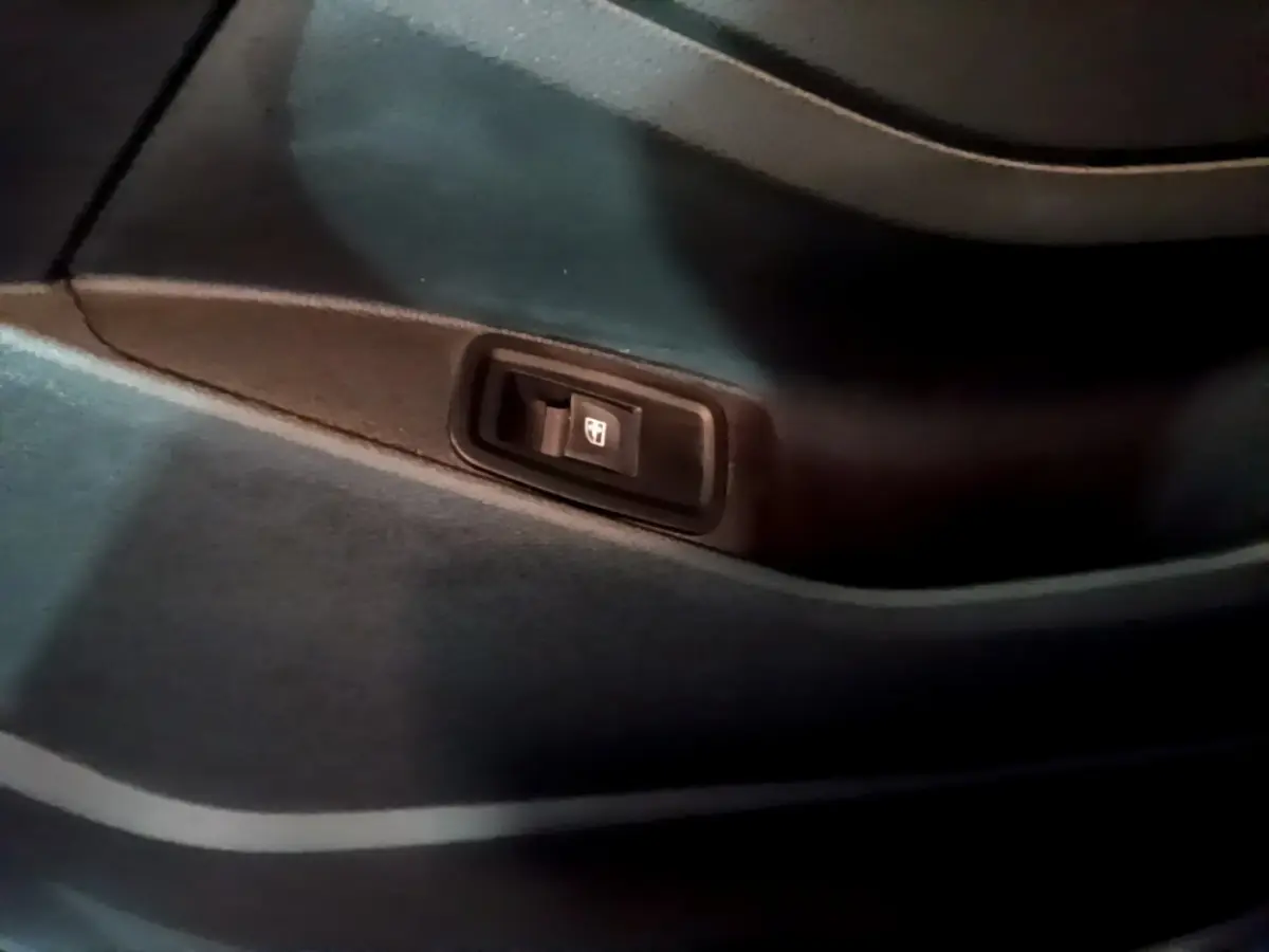 Gros plan sur l'interrupteur de lève-vitre intégré à la garniture intérieure noire d'une Renault Kangoo bleu 2023.
