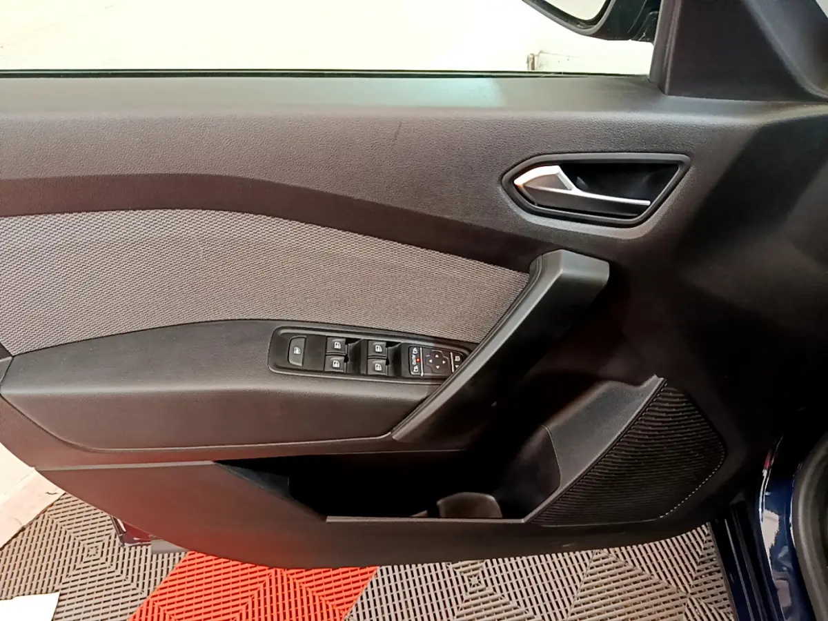 Vue rapprochée de la porte avant gauche du Renault Kangoo bleu 2023 avec commandes de vitres et poignée intégrée.