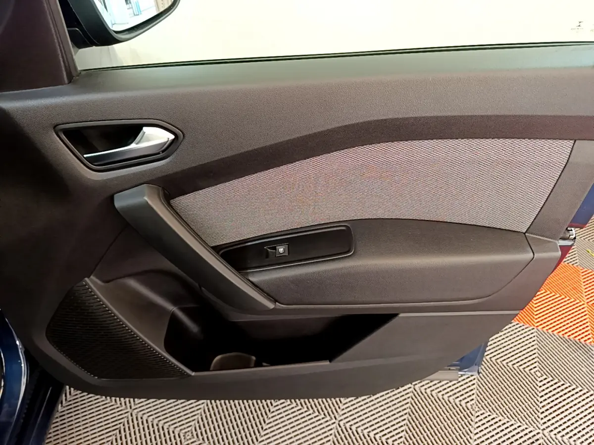 Porte intérieure côté gauche du Renault Kangoo Equilibre 2023 bleu, avec poignée argentée et bouton de lève-vitre.