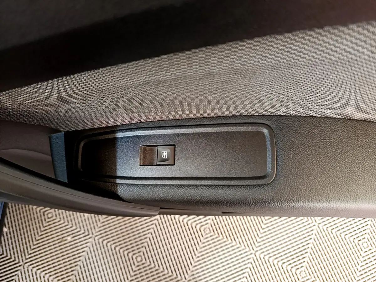 Bouton de commande de lève-vitre sur la portière intérieure d’un Renault Kangoo bleu 2023, vue rapprochée.
