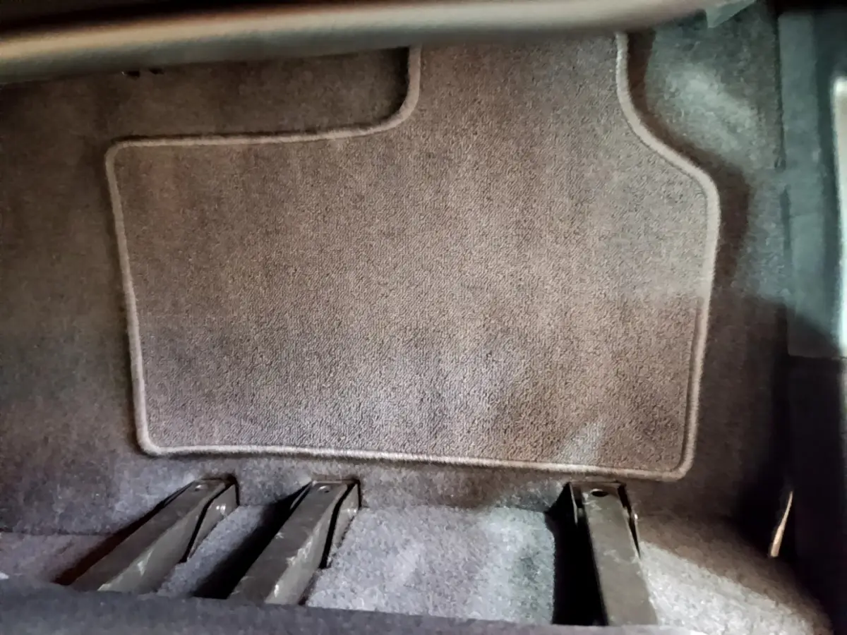 Gros plan sur le plancher arrière gris du Renault Kangoo bleu 2023, montrant les rails de fixation des sièges.