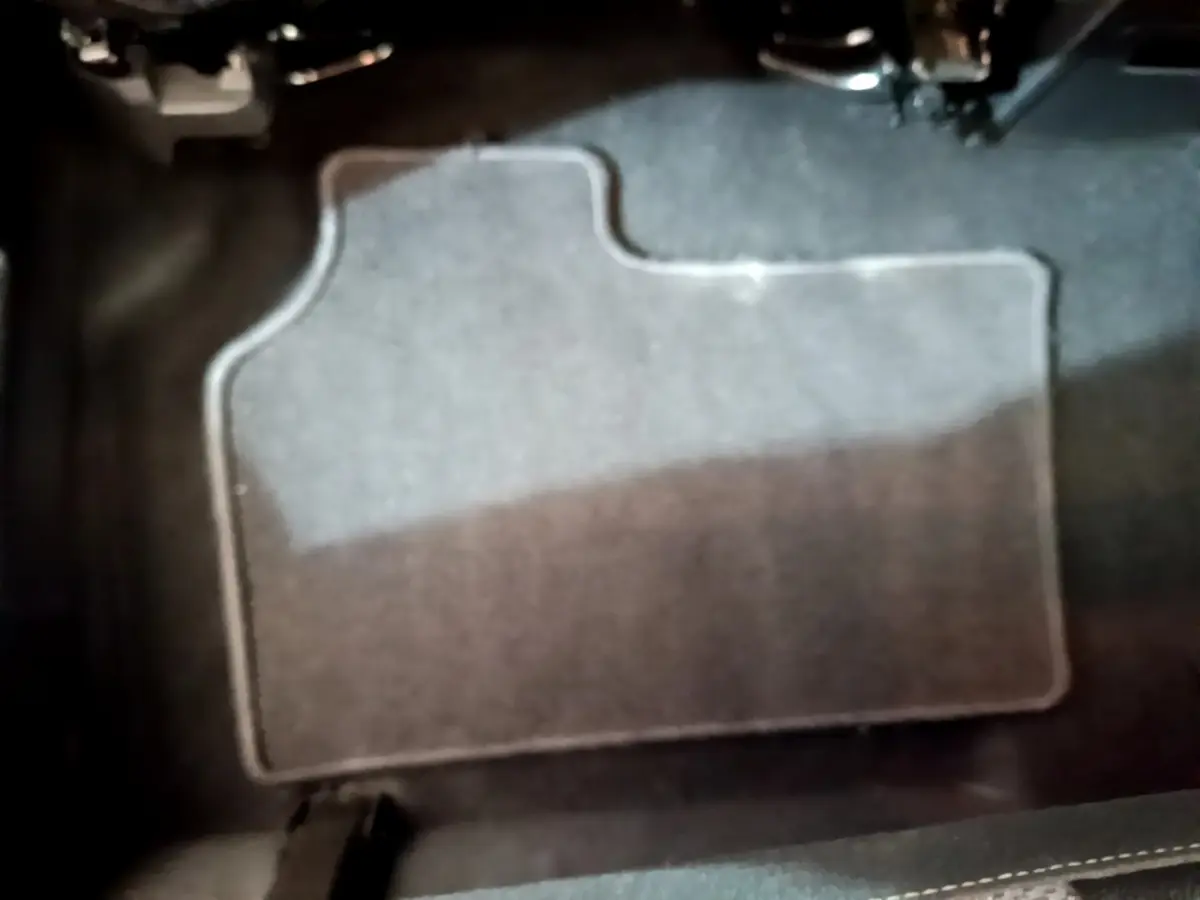 Tapis de sol gris foncé en gros plan sous les pédales du conducteur d'un Renault Kangoo bleu 2023.