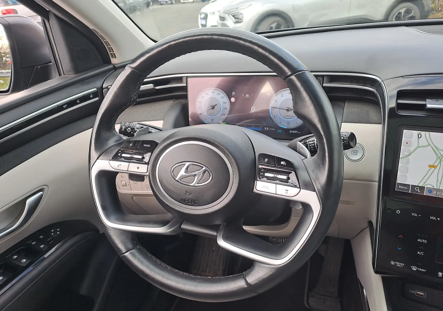 Vue intérieure centrée sur le volant cuir noir du Hyundai Tucson 2023 avec tableau de bord digital et écran tactile.