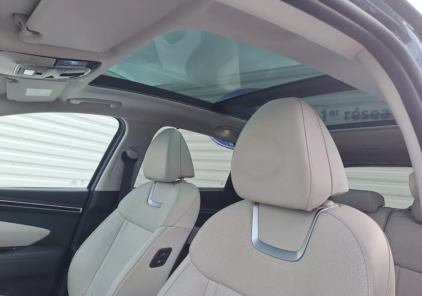 Intérieur beige clair du Hyundai Tucson 2023, vue côté gauche sur les sièges avant en cuir et toit panoramique vitré.