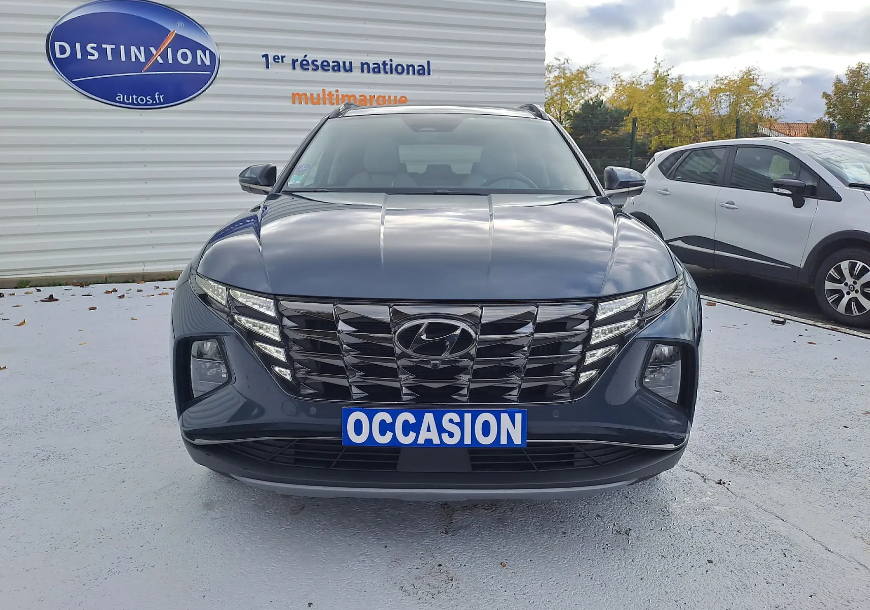 Vue frontale d'un Hyundai Tucson 2023 Cypress Green avec calandre noire et plaque "OCCASION" visible.