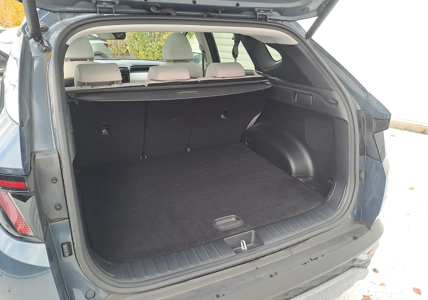 Coffre ouvert vu de l'arrière d'un Hyundai Tucson 2023 vert Cypress, montrant l'espace de chargement et les sièges beige.