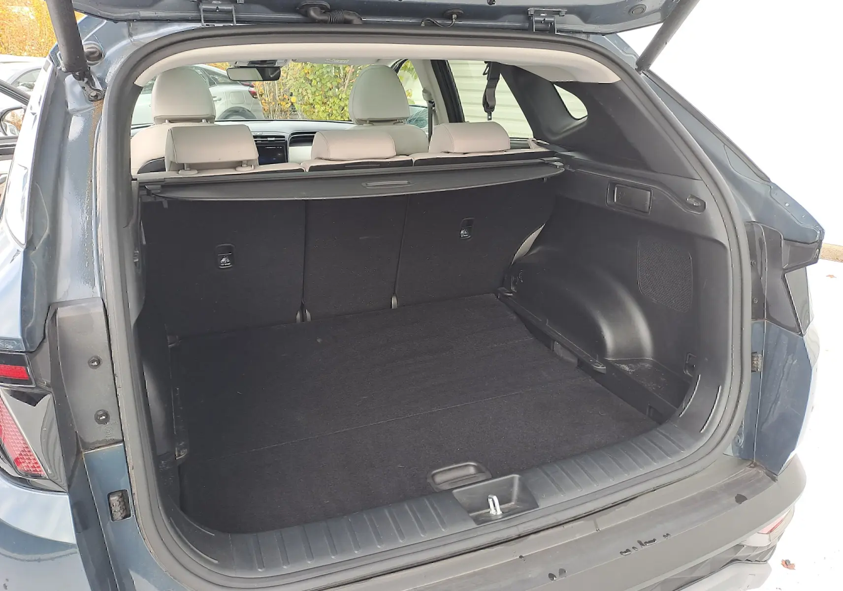 Coffre ouvert vu de l'arrière d'un Hyundai Tucson Cypress Green 2023, intérieur beige et espace de chargement vide.
