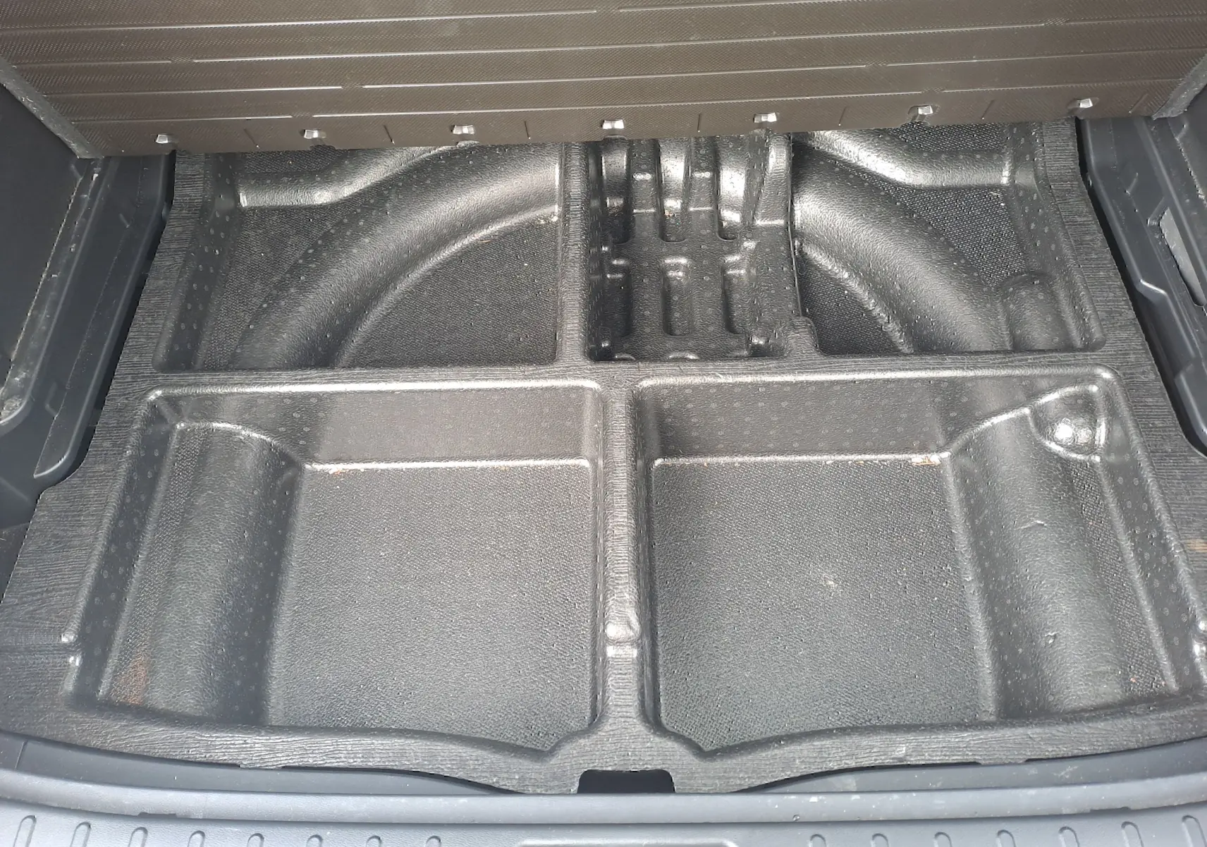 Compartiment de rangement noir sous le plancher du coffre du Hyundai Tucson 2023, version hybride Cypress Green.