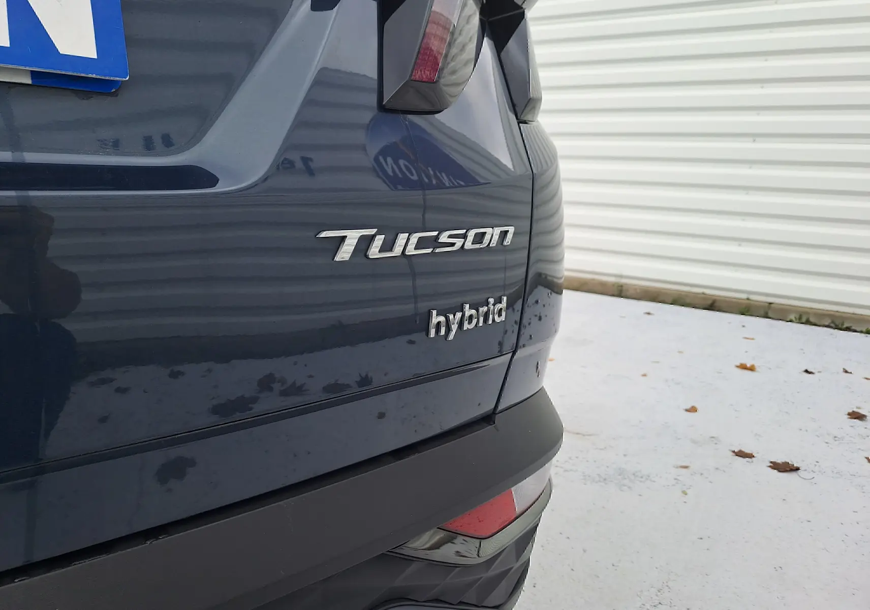 Gros plan sur l'arrière droit du Hyundai Tucson hybride 2023 en Cypress Green avec logo distinctif "Tucson" et "hybrid".