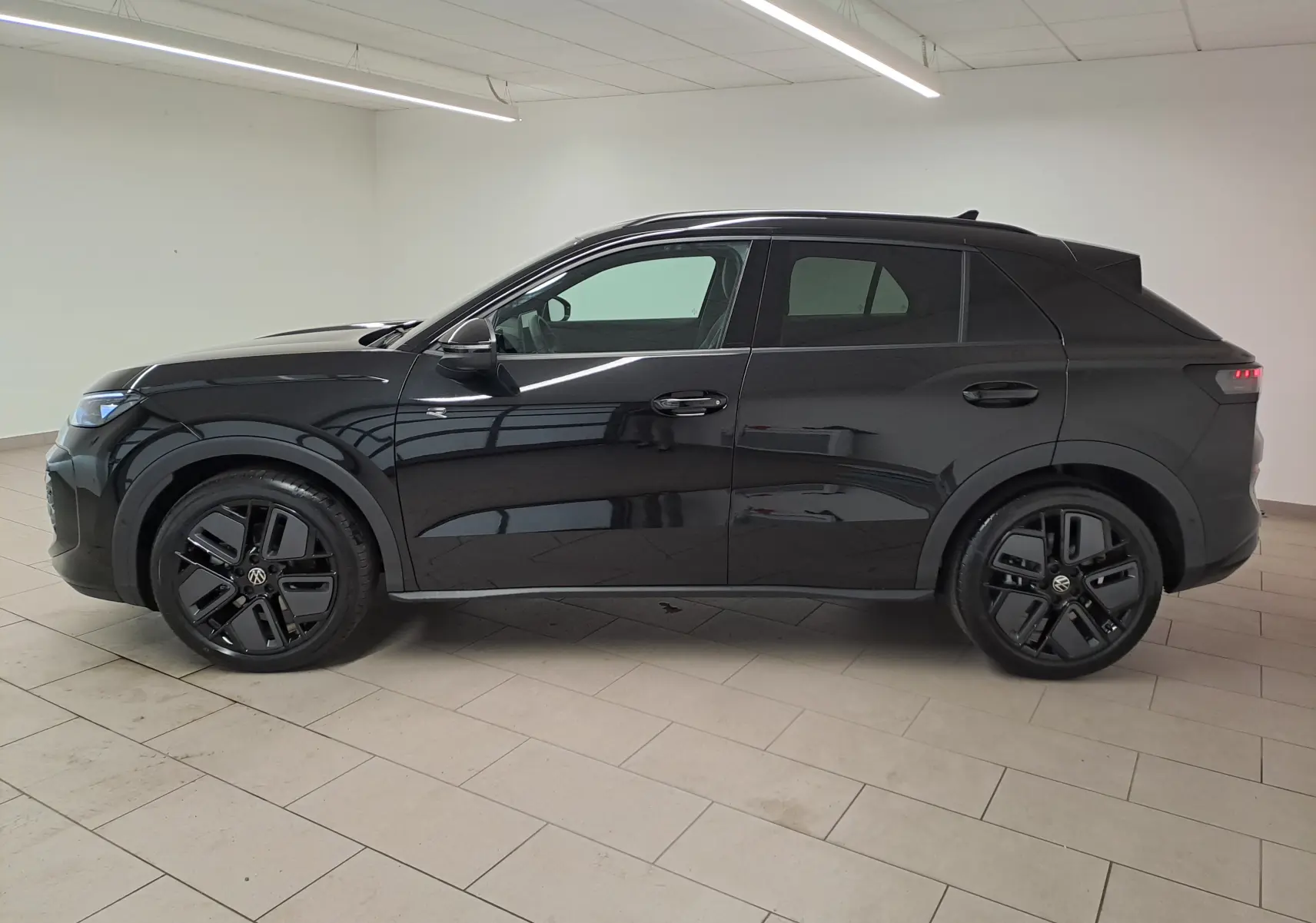 Profil côté gauche du Volkswagen T-Roc 2026 noir ébène avec jantes noires 19 pouces et phares LED matrix éteints.