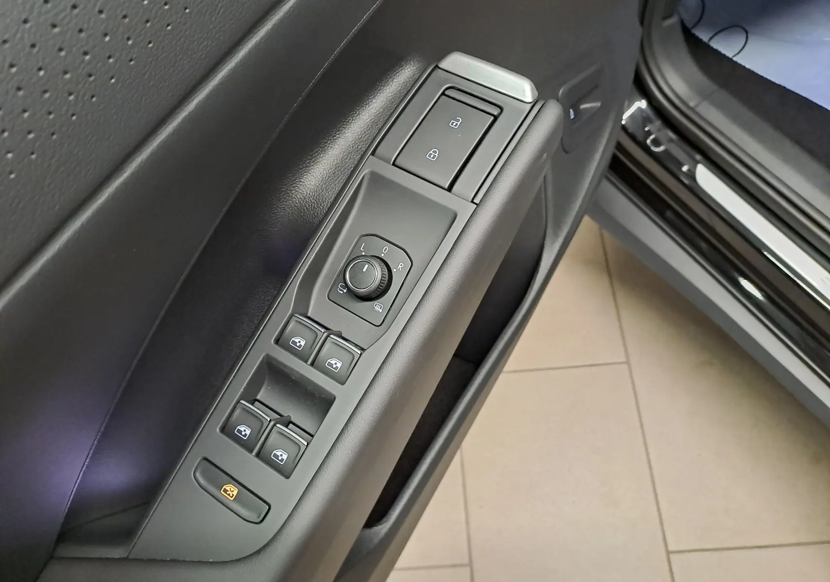 Gros plan sur les commandes de lève-vitres et rétroviseurs sur la porte côté conducteur du Volkswagen T-Roc noir ébène 2026.