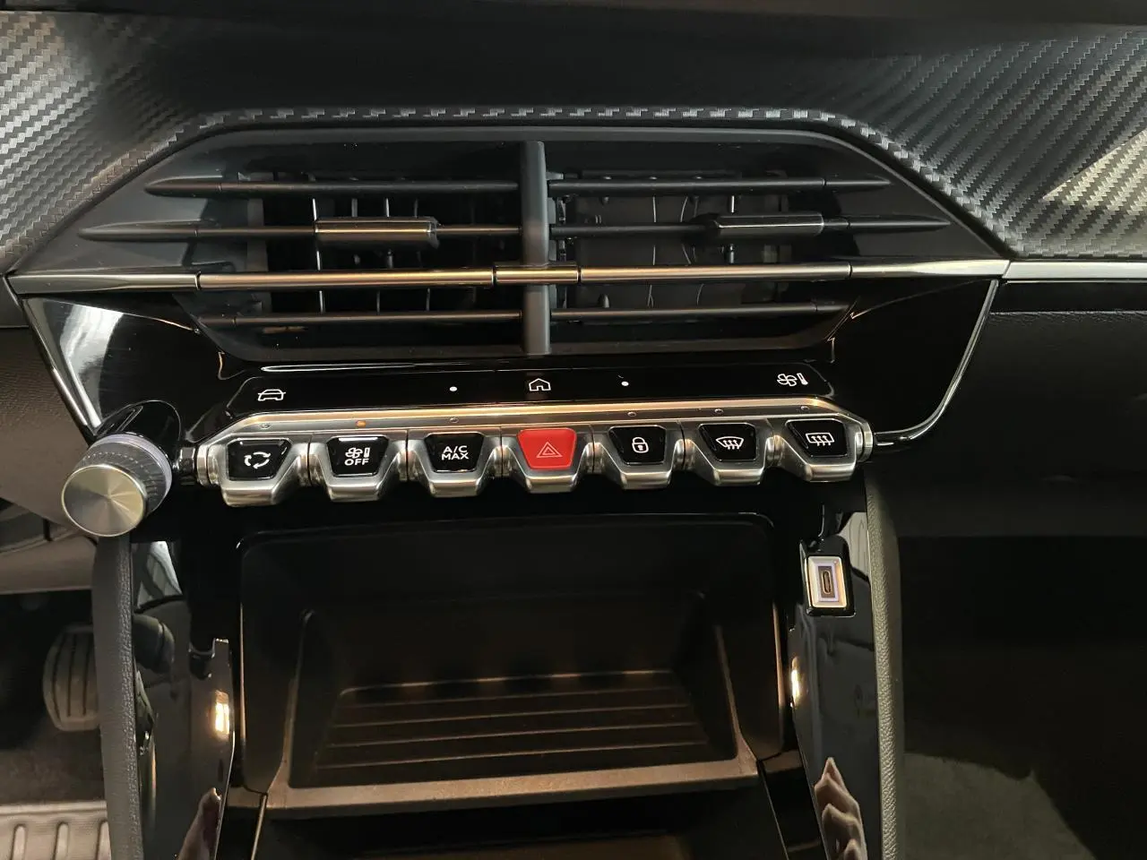 Vue rapprochée de la console centrale noire brillante avec commandes tactiles et boutons métallisés du Peugeot 208 gris clair 2024.