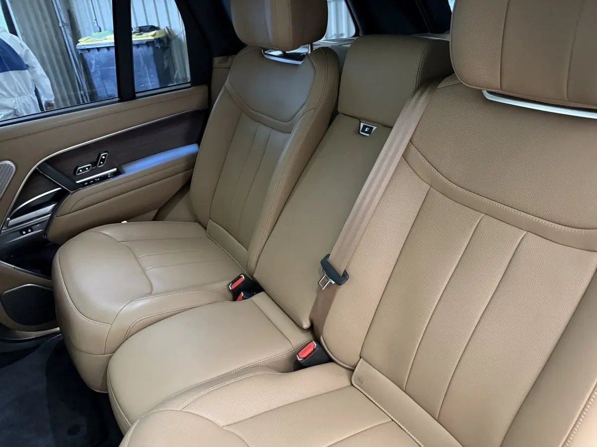 Vue intérieure côté droit des sièges arrière en cuir beige du Range Rover PHEV P550e Autobiography 2024.