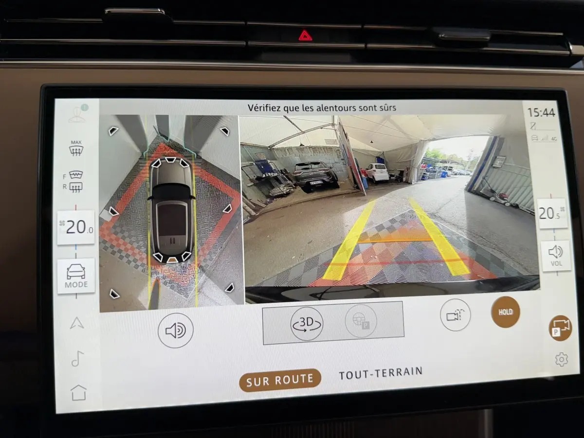 Écran tactile intérieur montrant la caméra 360° et vue arrière du Range Rover PHEV noir en stationnement.